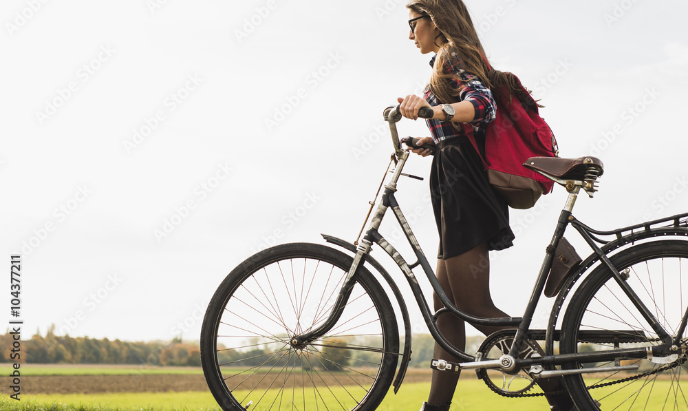 Young woman pushing her bicycle in rural landscape Young woman pushing her bicycle in rural landscape