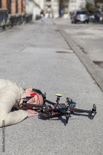 Pretty woman attacked by drone quadrocopter with bleeding head injuries, lying on sidewalk in the city, space for text