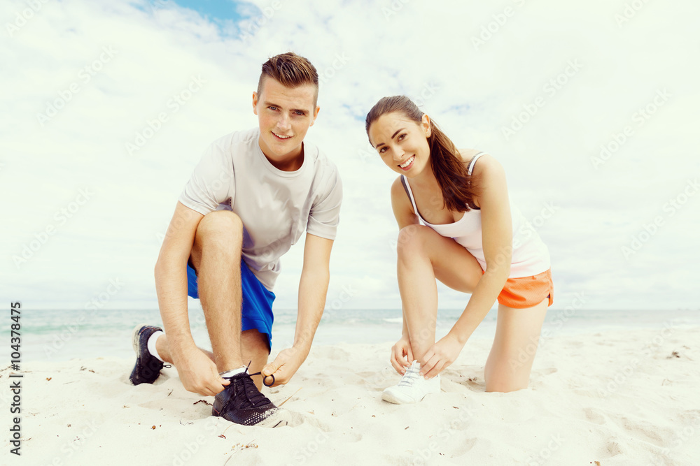 Fototapeta premium Runners. Young couple exercising and stertching on beach