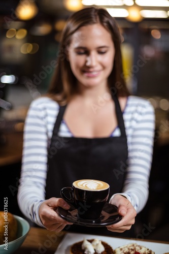Smiling barista holding coffee