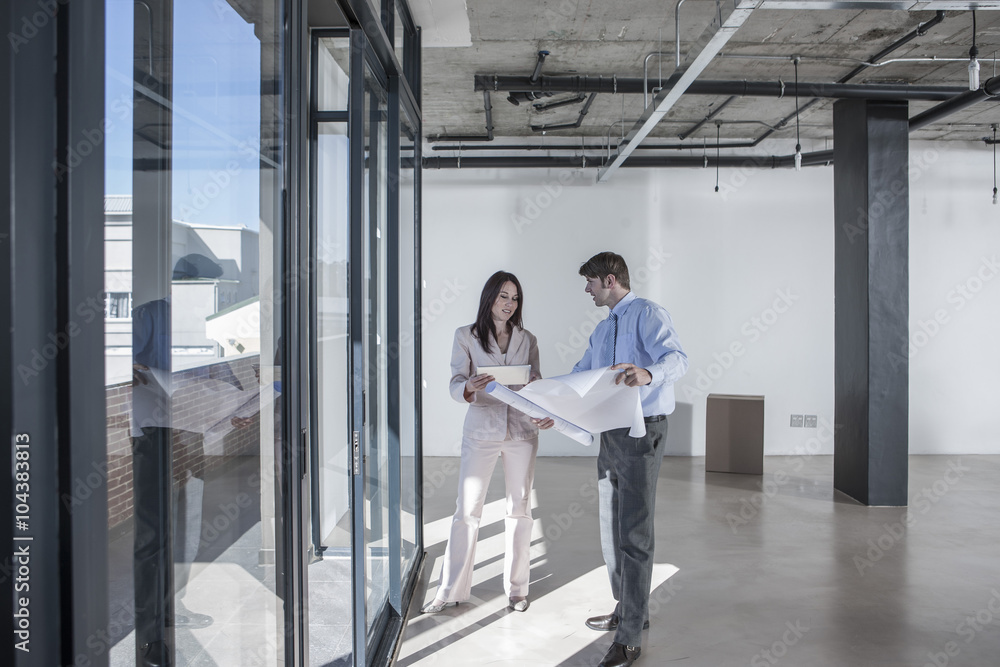 Businesspeople looking at construction plan in new open office Businesspeople looking at construction plan in new open office
