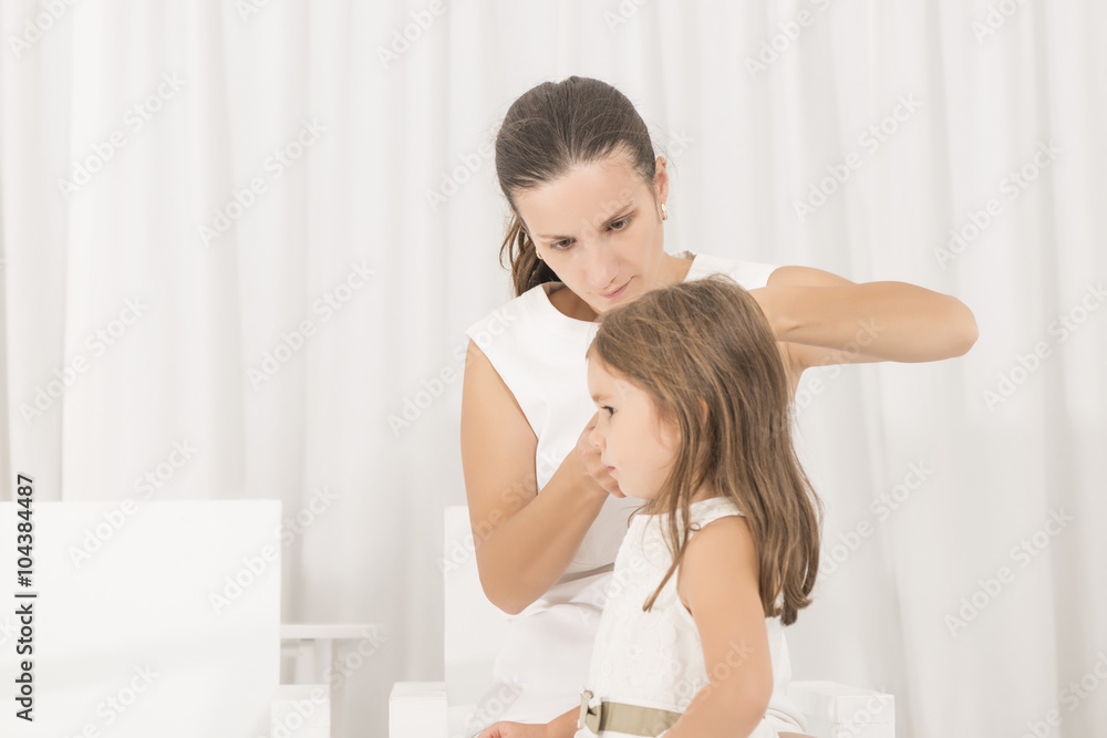 Portrait of expressive beautiful little girl and her mother arranging her hair Portrait of expressive beautiful little girl and her mother arranging her hair