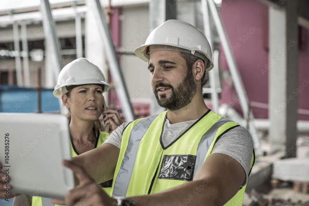 Woman in protective workwear and construction worker in construction site Woman in protective workwear and construction worker in construction site