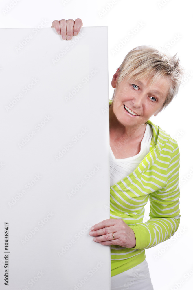 Glückliche ältere Frau steht hinter weißer Tafel Glückliche ältere Frau steht hinter weißer Tafel