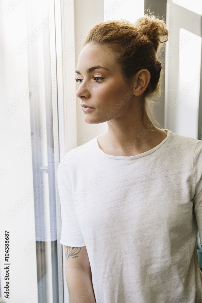 Young woman looking out of her window Young woman looking out of her window