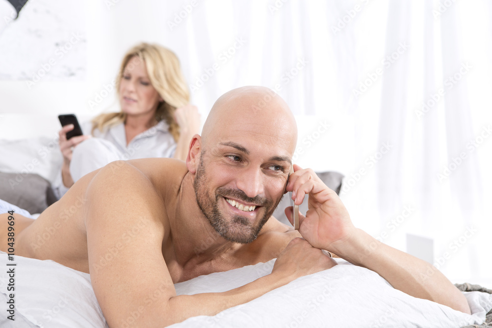 Mature couple in bedroom using their mobile phones Mature couple in bedroom using their mobile phones