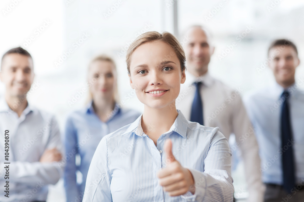 smiling businesswoman showing thumbs up in office smiling businesswoman showing thumbs up in office