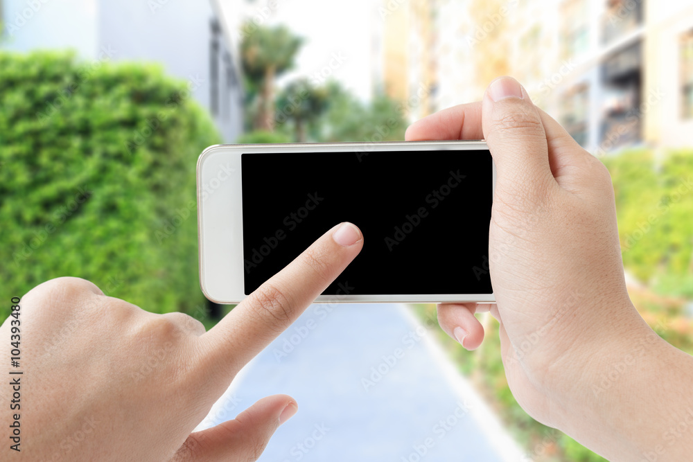 Female hand touching smartphone in garden