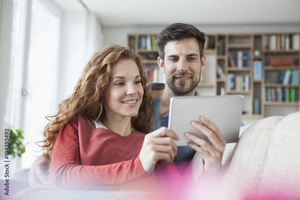 Relaxed couple at home on couch using digital tablet Relaxed couple at home on couch using digital tablet