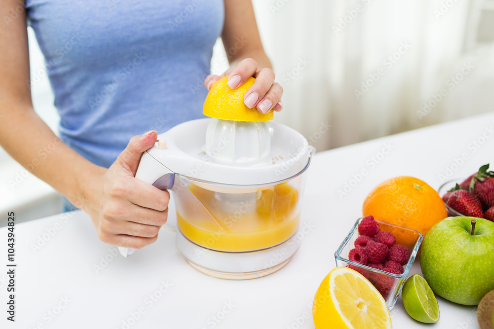 close up of woman squeezing fruit juice at home