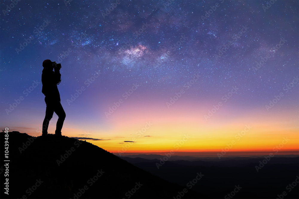 Silhouette of woman is taking the milky way photo on top of mountain