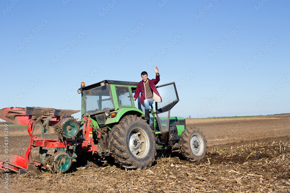 Obraz premium Farmer standing on the tractor
