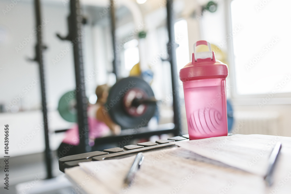 Shaker bottle with woman working out in the background Shaker bottle with woman working out in the background