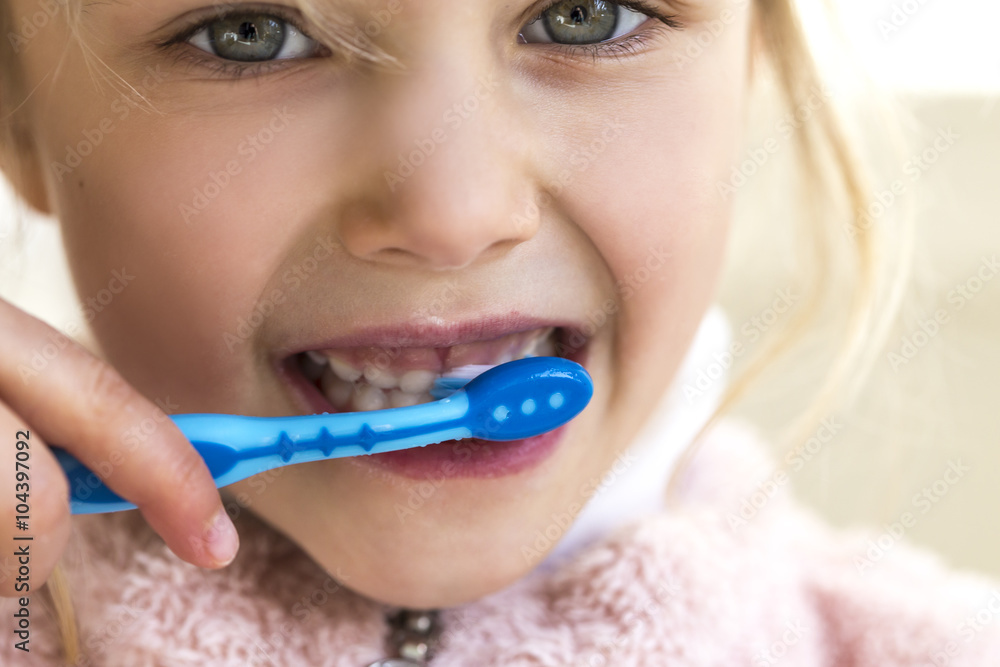 Little girl brushing her milk teeth, close-up