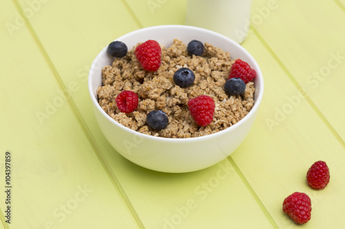 Granola in a bowl with milk, raspberries and blueberries