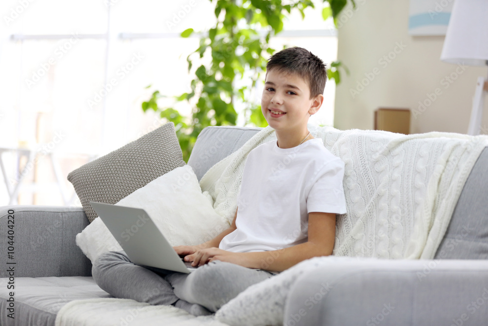 Little boy using laptop on a sofa at home Little boy using laptop on a sofa at home