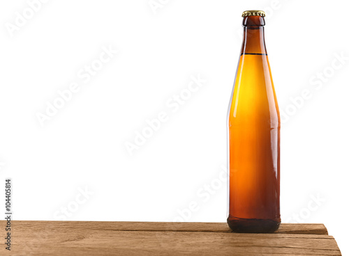 Unlabeled beer bottle on wooden table against white background