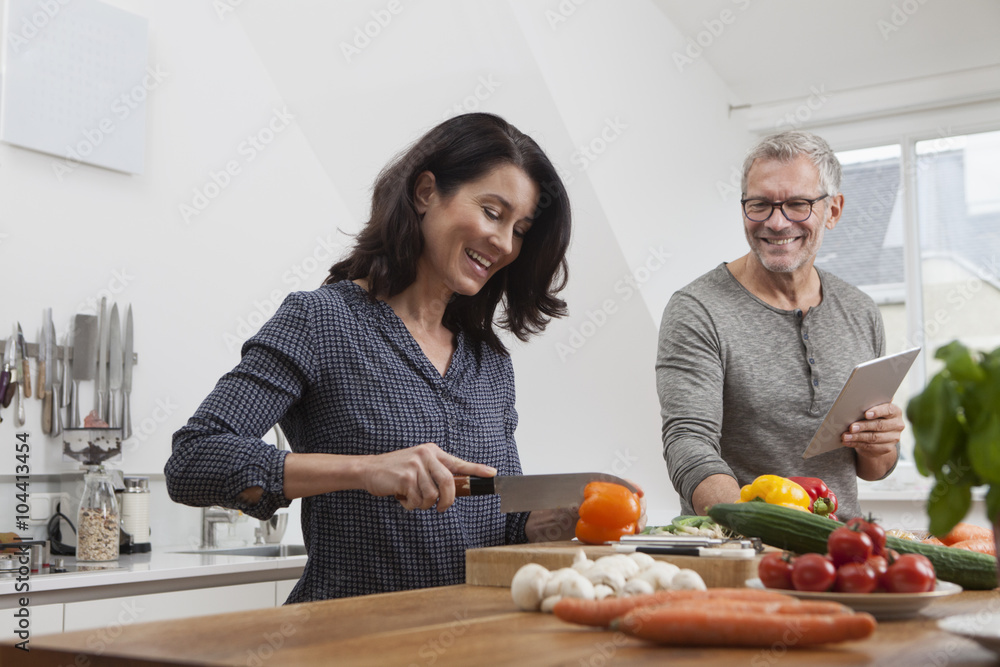 Mature couple with digital tablet cooking in kitchen Mature couple with digital tablet cooking in kitchen