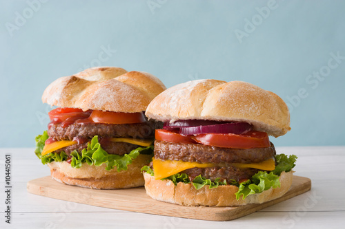 Delicious burgers with cheddar cheese, tomato, lettuce and onion
