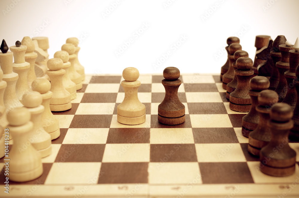 Two pawns on a chessboard. Light and dark. Confrontation. Against each other. Forehead to forehead. Vintage toning. Two pawns on a chessboard. Light and dark. Confrontation. Against each other. Forehead to forehead. Vintage toning.