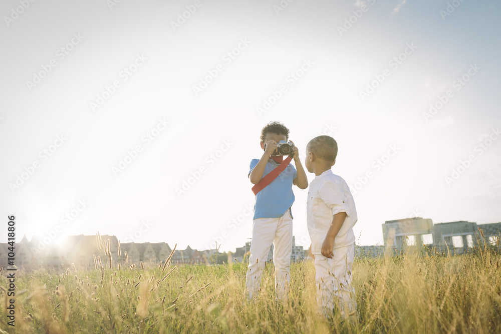 Germany, Cologne, boy taking picture of his brother in a field Germany, Cologne, boy taking picture of his brother in a field