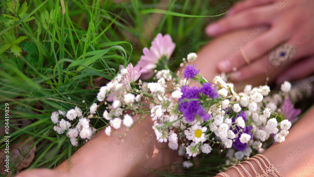 Girl's feet in grass with fresh flowers and gold jewellery Girl's feet in grass with fresh flowers and gold jewellery