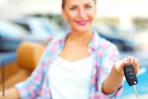 Young woman standing near a convertible with keys in hand