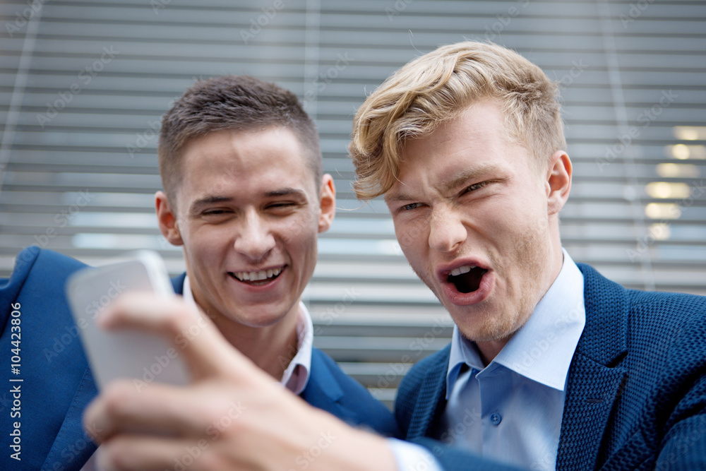 Two happy businessmen looking at cell phone Two happy businessmen looking at cell phone