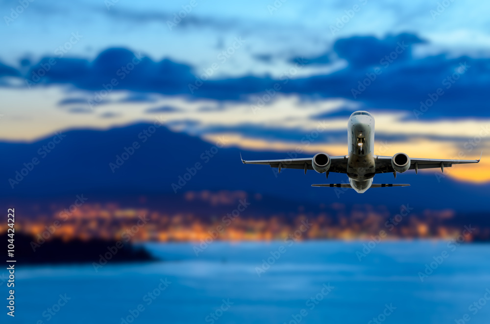 Fototapeta premium Night (dawn, dusk ) flight of the airplane (jet) over the beautiful night sky and city over ocean.