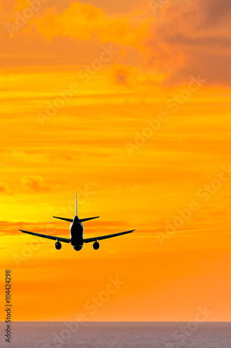 Sunset or sunrise (dawn, dusk ) flight of the airplane (jet) over beautiful sky and ocean. © karamysh