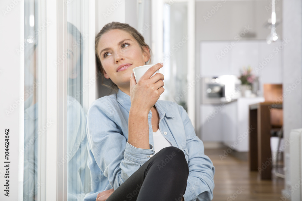 Young woman sitting at the window, drinking coffee Young woman sitting at the window, drinking coffee