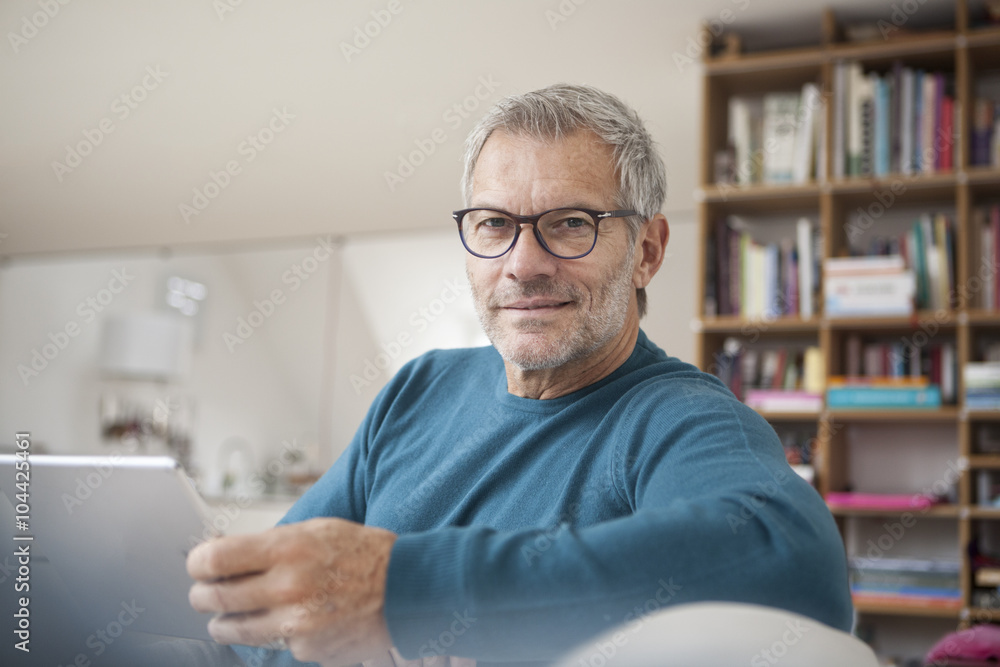 Portrait of mature man at home holding digital tablet Portrait of mature man at home holding digital tablet