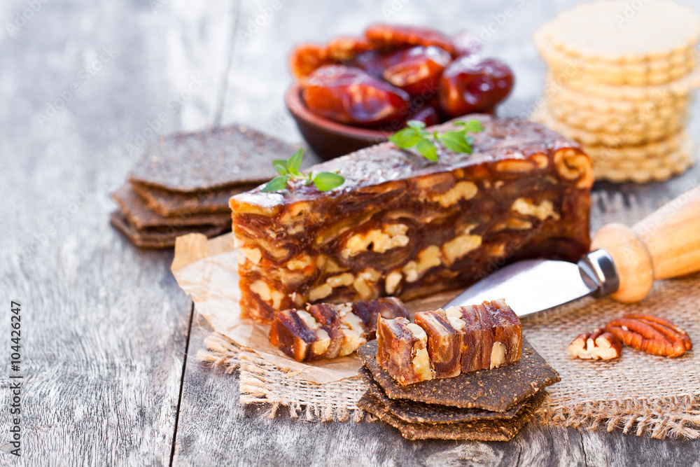 Fototapeta premium Date walnut wedge with multigrain crackers on wooden table