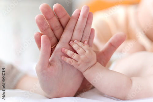 father and mother hold in their hands a little newborn baby's ha
