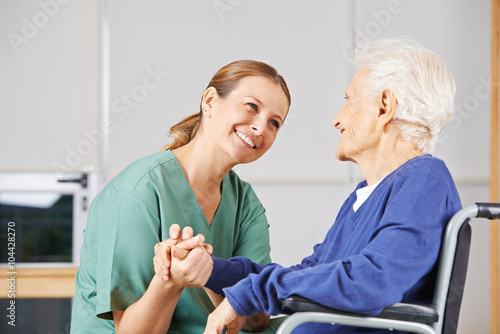 Krankenschwester hält Hand einer Seniorin photo