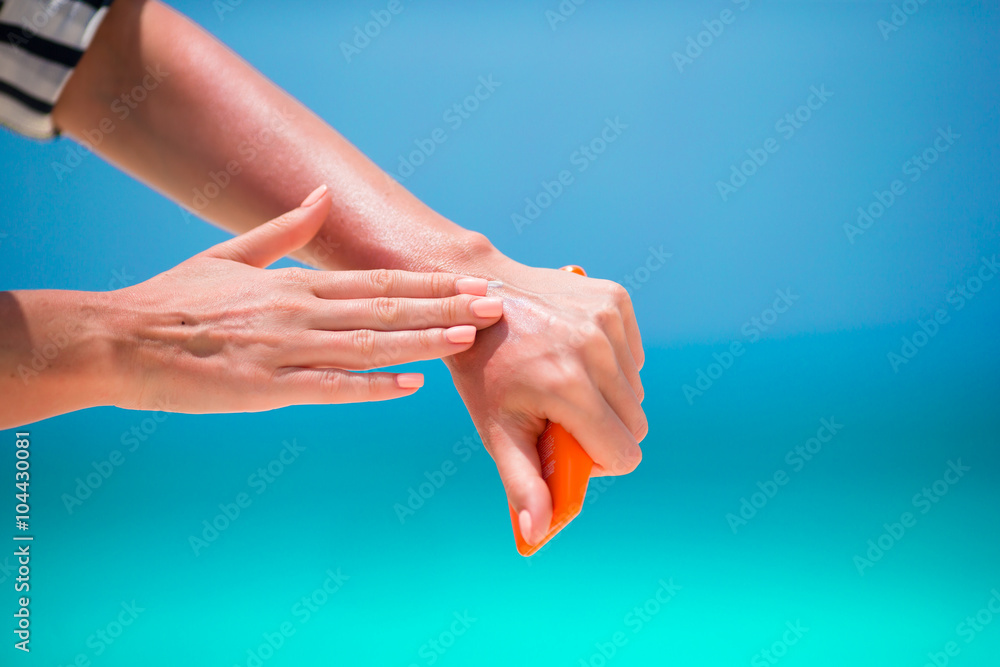 Female hands with suncream bottle background blue sea Female hands with suncream bottle background blue sea