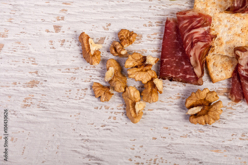 Ham, nuts, crackers and grape on white wooden background