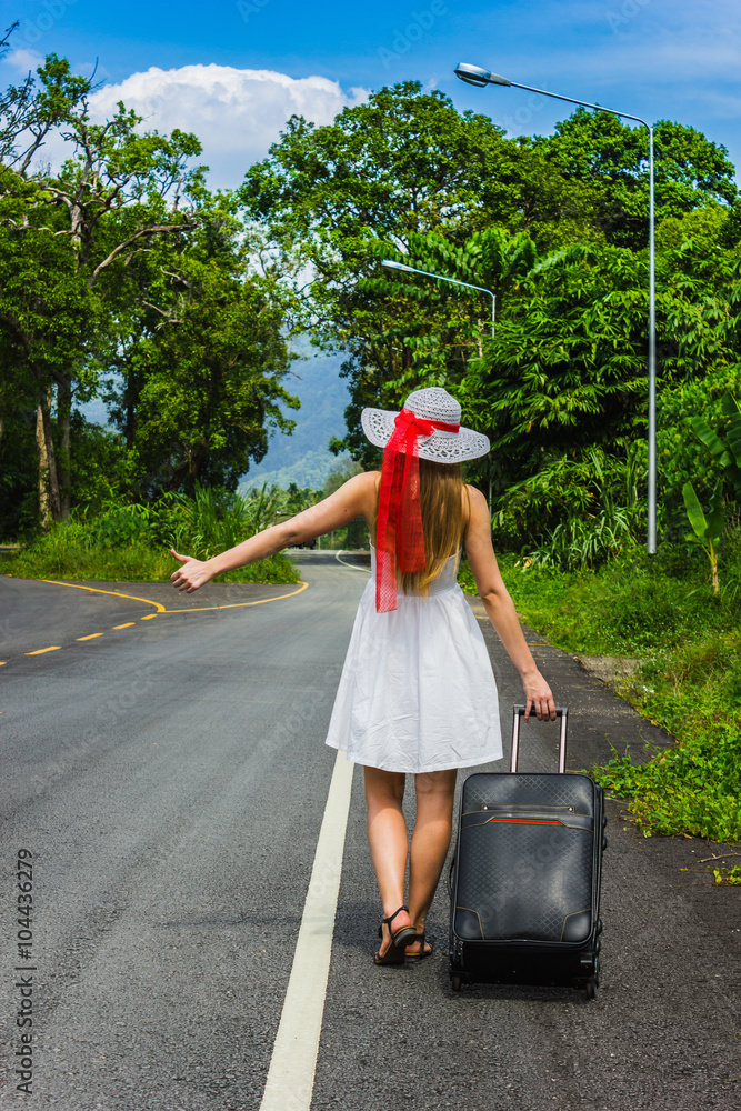 Obraz premium Girl with a suitcase on a deserted road