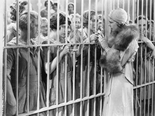 Tableau sur toile One woman standing in front of a jail talking with a group of women