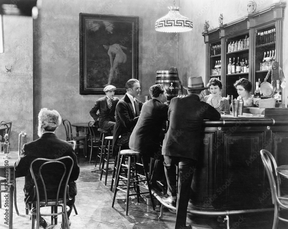 Men sitting around a counter in a bar  - obrazy, fototapety, plakaty 