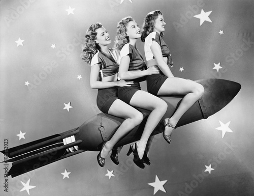 Three women sitting on a rocket 