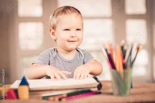 Blond boy laughing and crayons in front