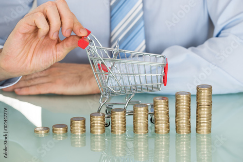 Foto Businessman With Stacked Coins And Small Shopping Cart