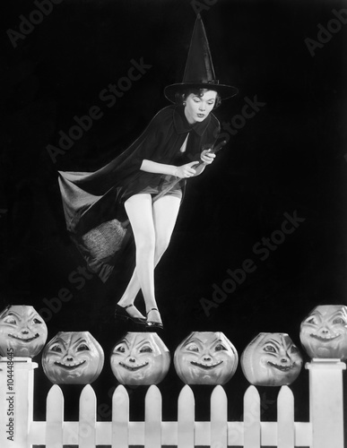Foto Young witch hovers on her broom, eyeing which pumpkin to choose