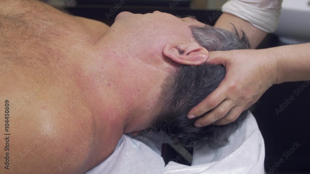 Close up of masseuse hands make therapeutic massage of head to adult fat man. Close up of masseuse hands make therapeutic massage of head to adult fat man.