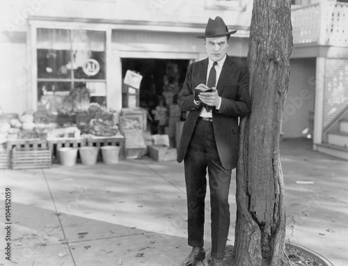 Fotografie Detective leaning against tree taking notes