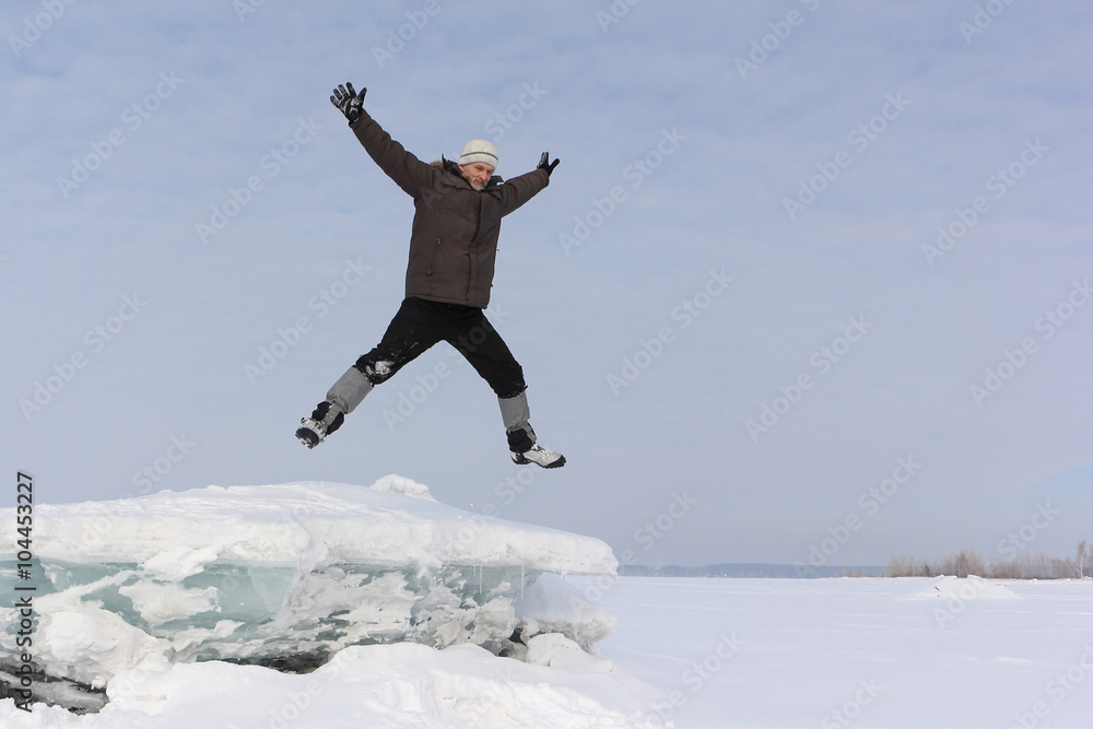 The man with a beard in a gray cap jumping from an block of ice in the snow
The man with a beard in a gray cap jumping from an block of ice in the snow