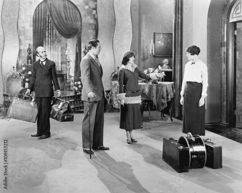Four people standing in a the lobby of a hotel with luggage  photo