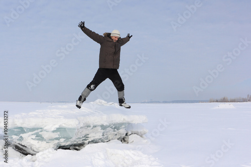 The man with a beard in a gray cap jumping from an block of ice in the snow 