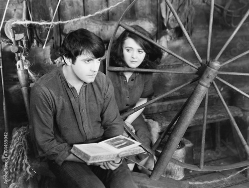 Young man reading a book and a young woman sitting beside him 